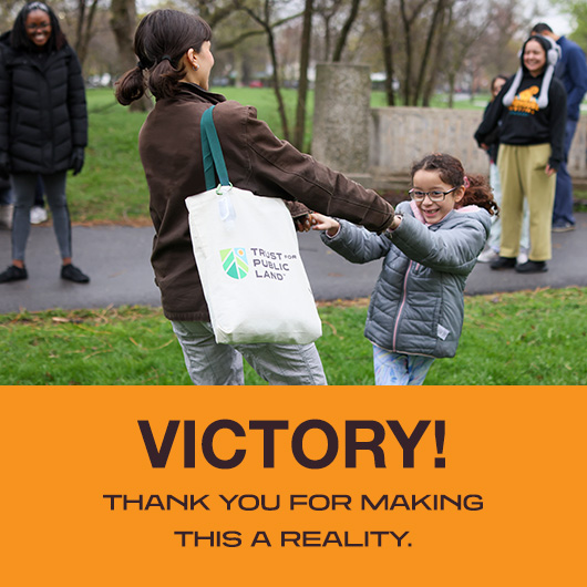 Child and adult hold hands in celebration of a public lands victory.