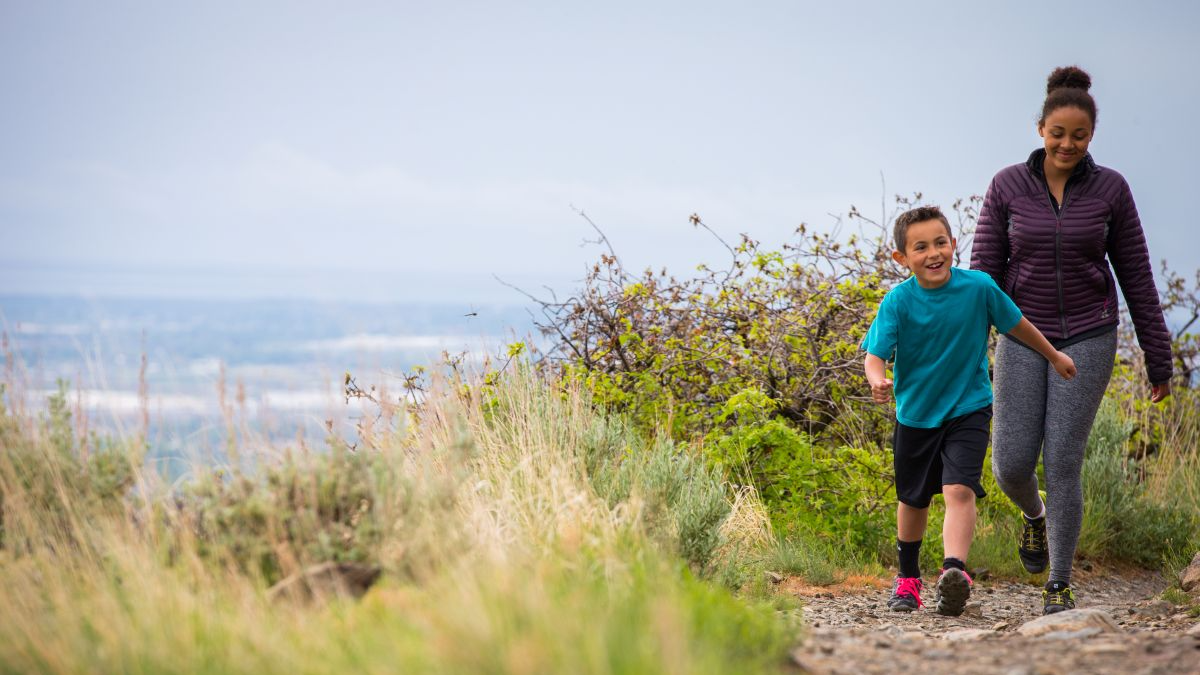 Child and adult walking on hiking trail.